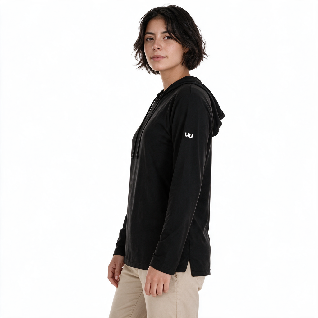 Vista lateral de mujer con sudadera Blizzard negra TUUM y pantalón beige arena, mostrando la capucha, el corte de la prenda y el logotipo blanco en la manga.