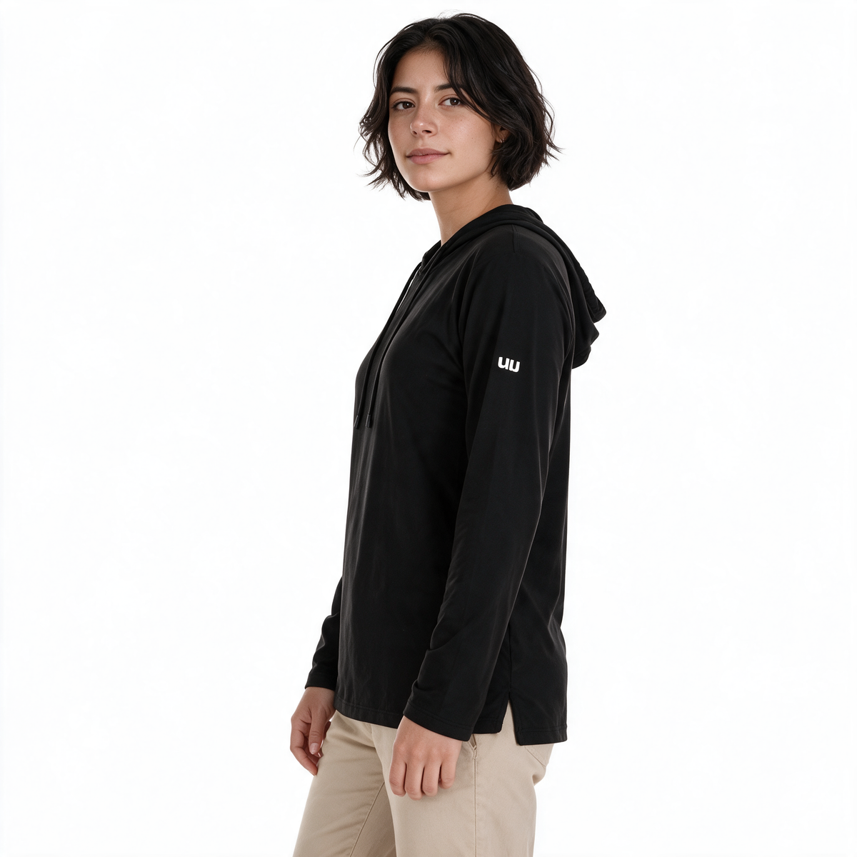 Vista lateral de mujer con sudadera Blizzard negra TUUM y pantalón beige arena, mostrando la capucha, el corte de la prenda y el logotipo blanco en la manga.