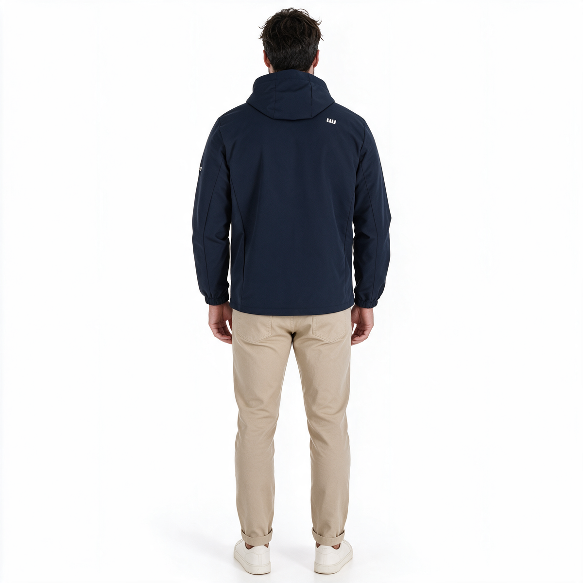 Hombre modelando chamarra TUUM Peak azul marino abierta sobre camiseta blanca, con capucha, pantalón beige y tenis blancos en fotografía de estudio.