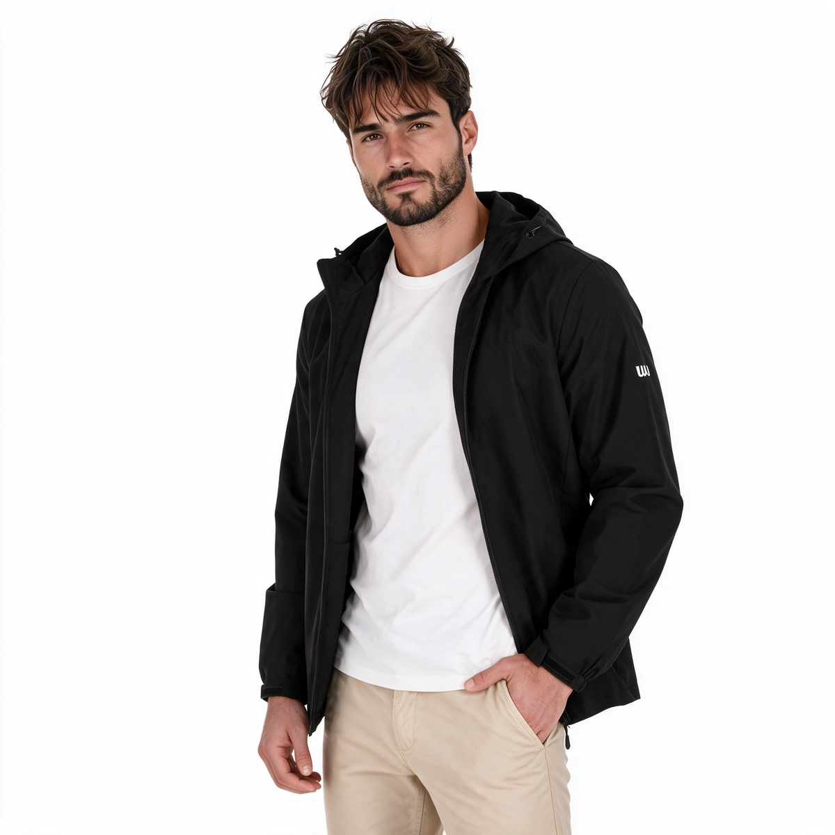 Hombre modelando chamarra TUUM Peak negra abierta sobre camiseta blanca, con capucha, cierre frontal y pantalón beige, en fotografía de estudio con fondo blanco.