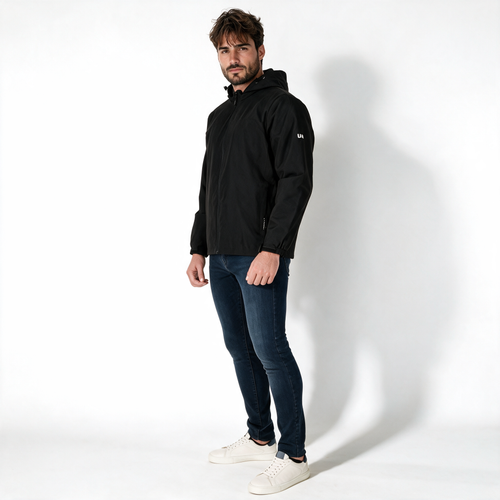 Vista lateral de chamarra TUUM Peak negra para hombre con capucha, cierre frontal y logotipo blanco en manga, combinada con pantalón beige sobre fondo blanco.